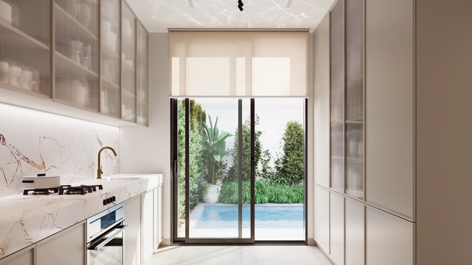 Modern kitchen with marble countertops and glass doors leading to a poolside garden, blending indoor luxury with outdoor beauty.